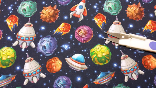 Detalle tela infantil con dibujos de cohetes y meteoritos